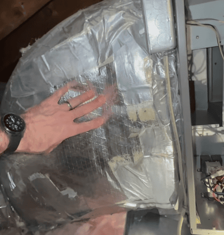 Professional inspecting a duct surface for potential mold growth, with a hand touching the duct as the HVAC system is evaluated.