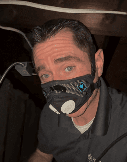 John Skelly wearing a respirator while conducting an inspection in a crawlspace.