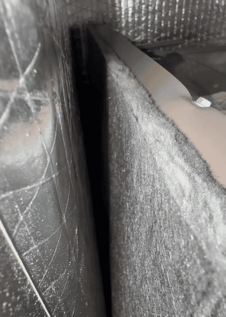 Air handler interior showing heavy dust and particulate buildup along the surface and inside the HVAC system