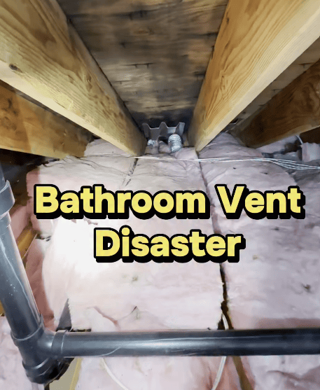 Bathroom vent exhausting into attic near insulation and roof framing, creating a potential moisture problem